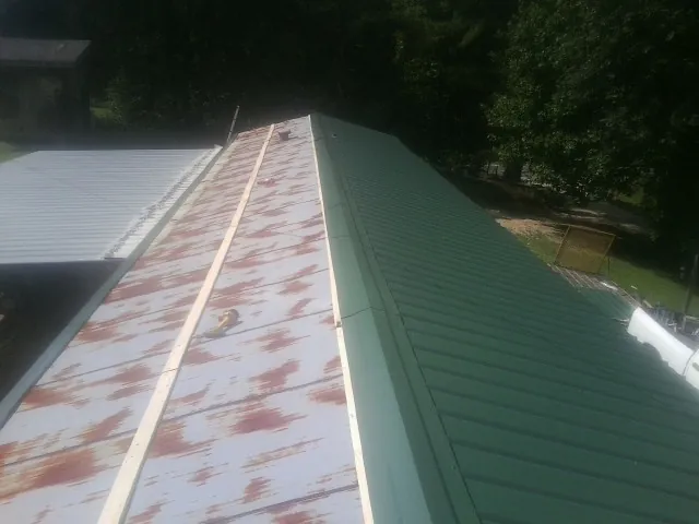 Old rusted panels beside newly installed green metal roofing — Wind Damage Roof Repair by Roofing Brothers in Kewaskum