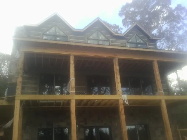 Dormers and porch framing on a large log home under construction — Roof Coating work by our crew in Kewaskum