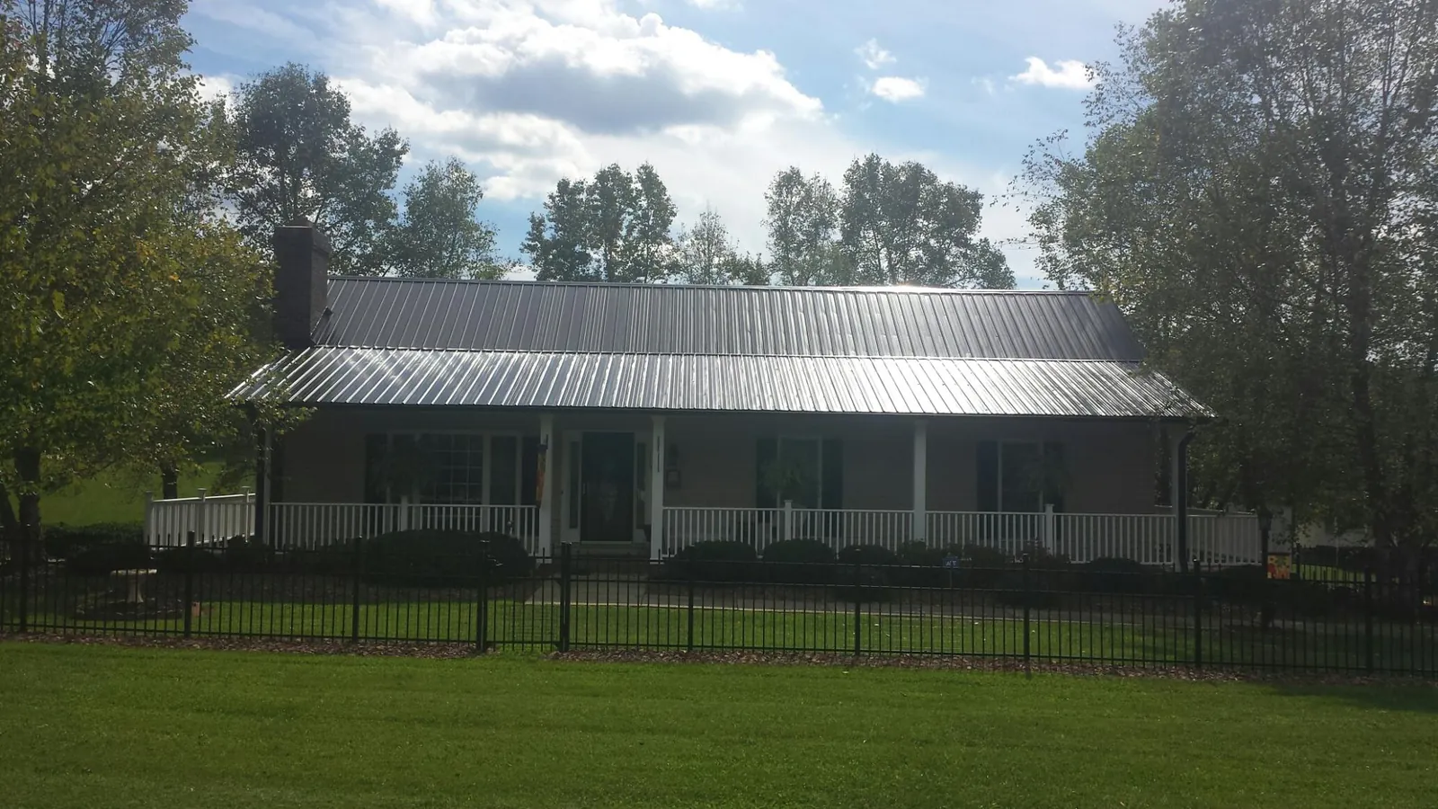 Gray metal roof on a brick ranch with a full width front porch — Gutter Guard Installation work by our crew in Kewaskum