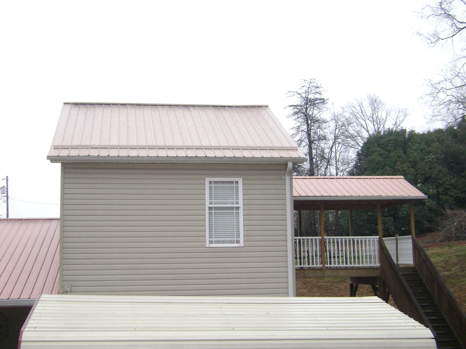 Tan metal roofs on a two story addition and attached porch, from a Roof Replacement job in Kewaskum